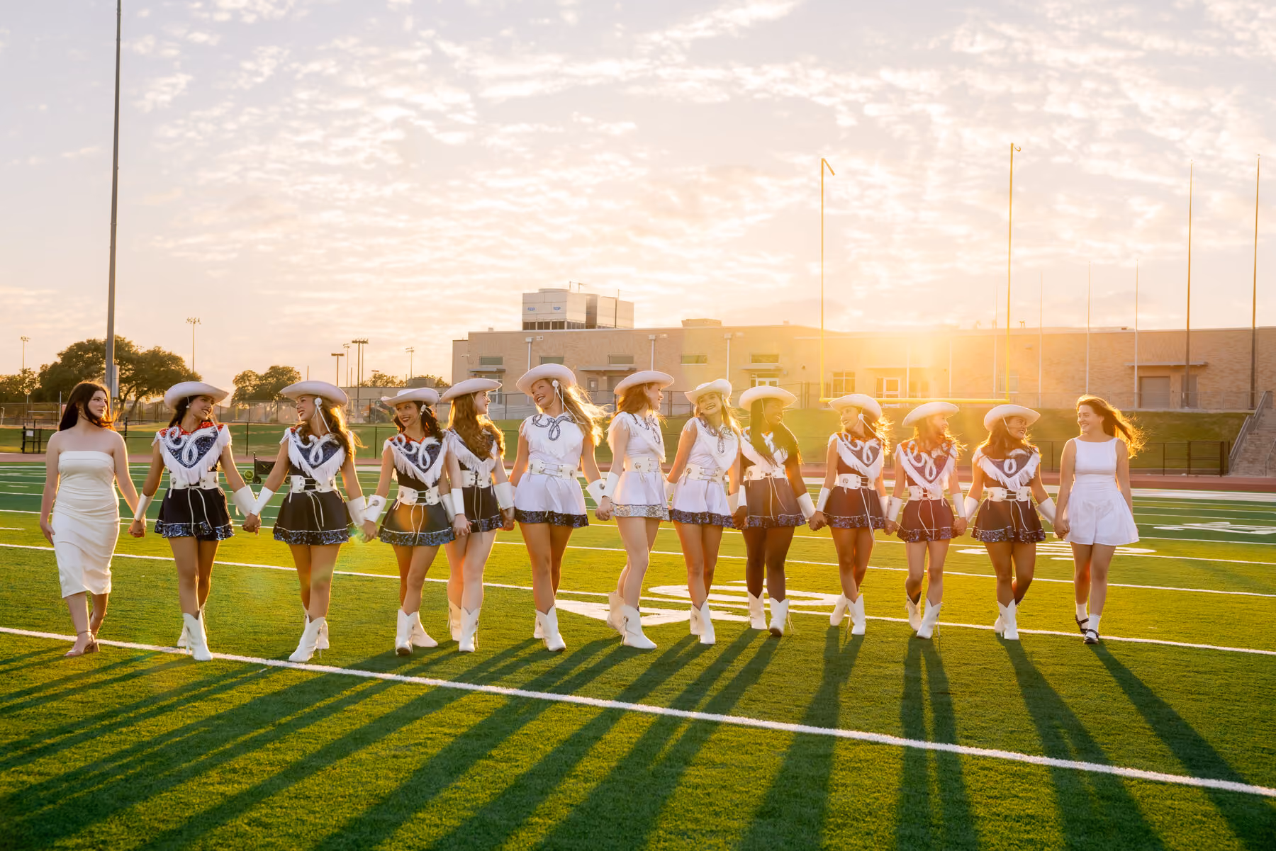 Dancers walking the field arm in arm at golden hour