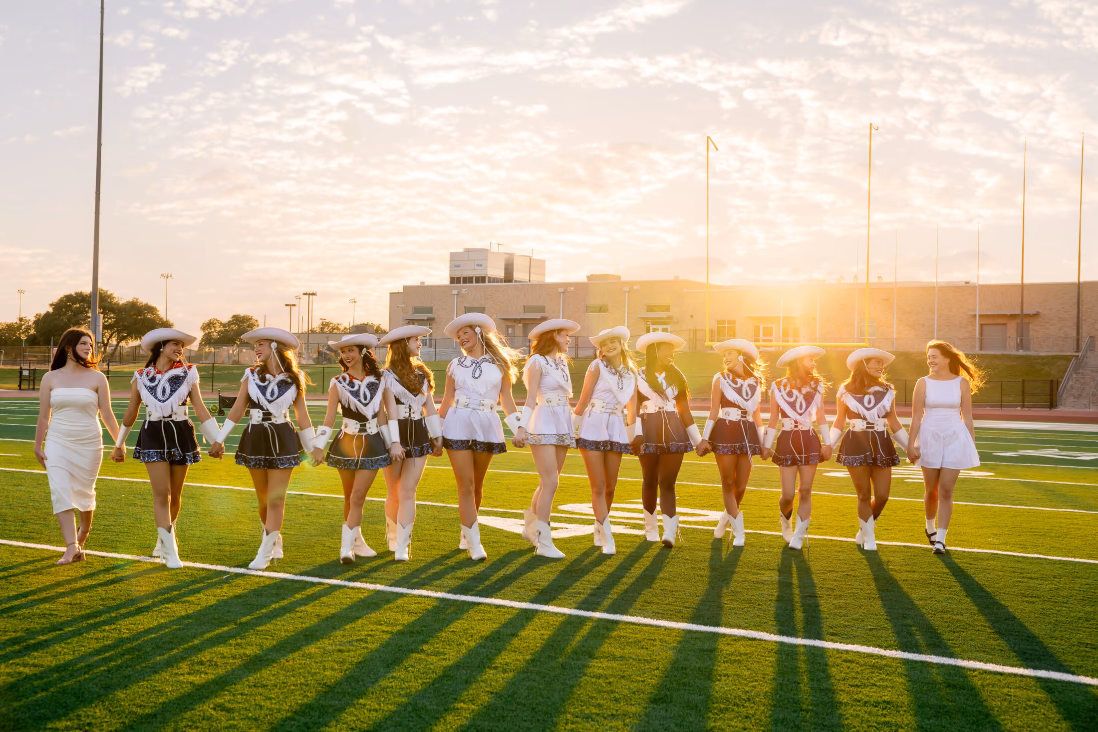 Dancers walking the field arm in arm at golden hour